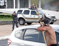Uneasy standoff; Policeman and indigenous man with bow & arrow, in Brasília.