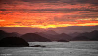 Fiery sunrise as a boat traverses Guanabara Bay toward Rio de Janeiro.