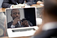 Businessman checks email and notes during a corporate meeting.