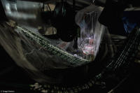 Pororoca expedition member reads by lantern while traversing the Amazon River at night.