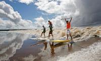 Trio of surfers ride the Pororoca bore wave inland, some 30 miles from the ocean.