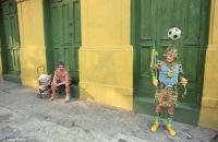 Costumed fan during the World Cup, observed by a homeless man.