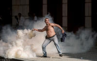 Protester throws back tear gas at Police near the stock exchange in Rio.