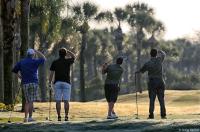 Golf foursome follow a tee shot just after sunrise.